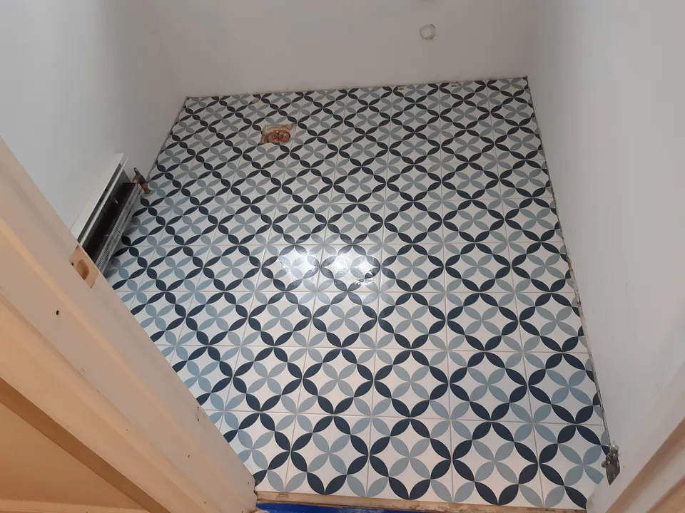 Small room floor covered in blue, navy and white patterned tile, seen from the doorway